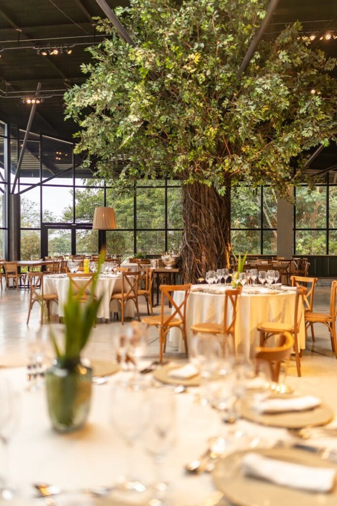 Stylish restaurant interior with round tables and chairs around a central tree display.
