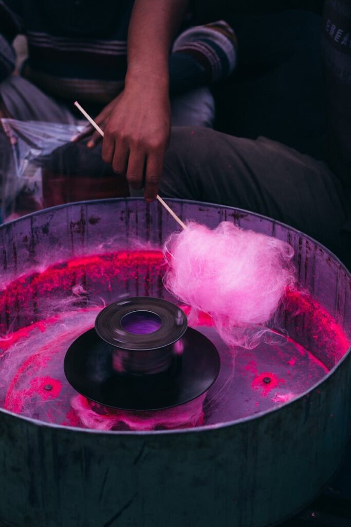 Close-up of a vendor making pink cotton candy using traditional equipment in Rangpur, Bangladesh.