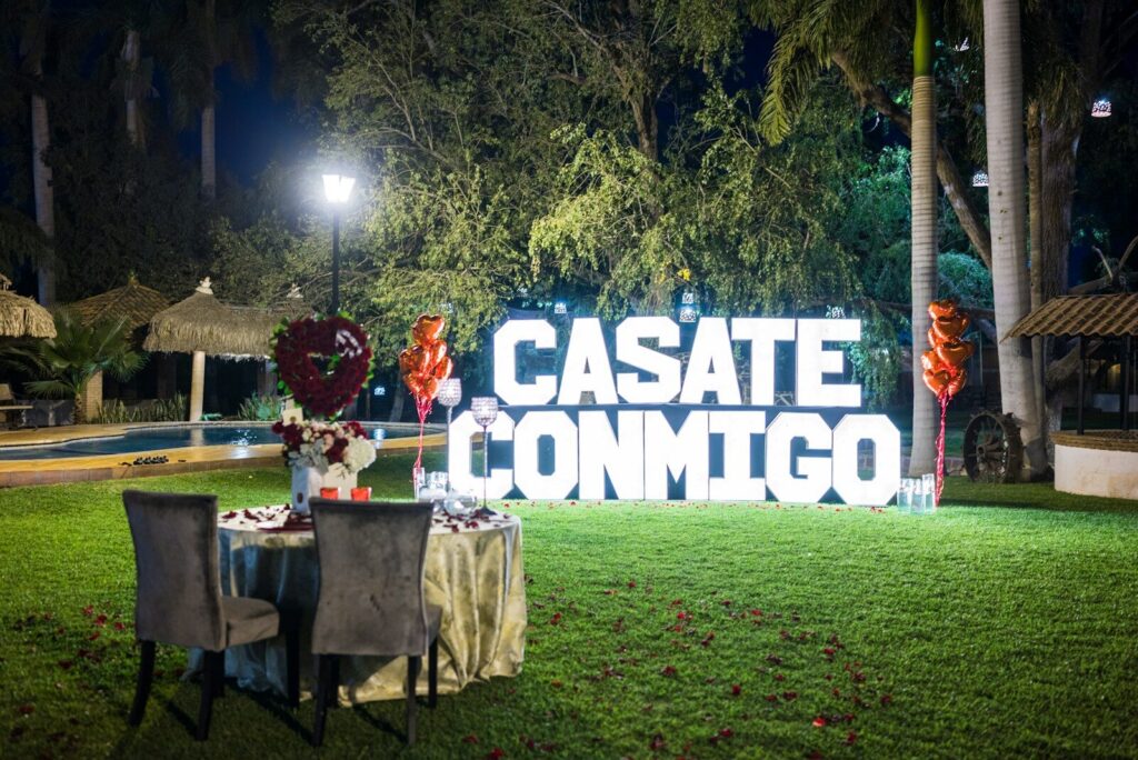 Large illuminated letters spell "casate conmigo" at night.